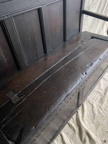An antique and uncommon 17th century carved oak tavern box settle