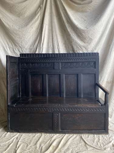 An antique and uncommon 17th century carved oak tavern box settle