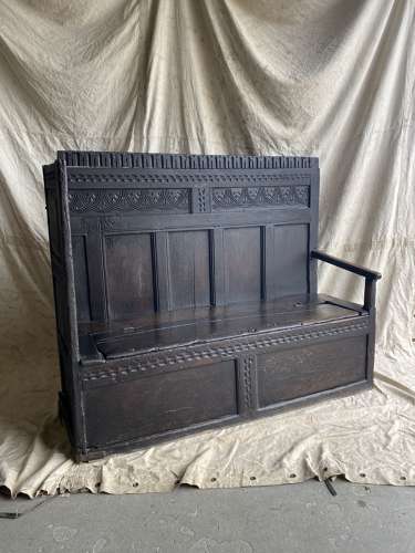 An antique and uncommon 17th century carved oak tavern box settle