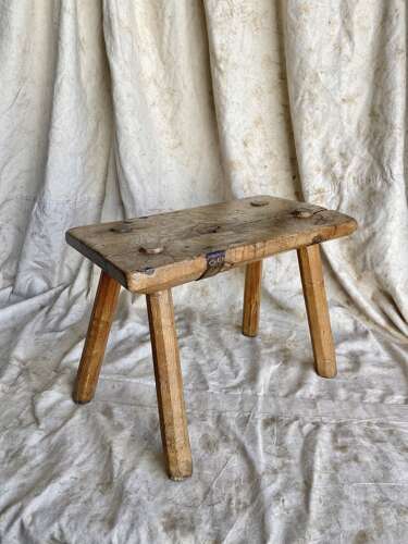 An antique Georgian elm dairy stool with iron strap repair